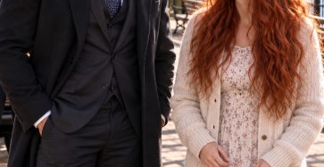 Two adults speaking on an autumn riverside walkway, with no children shown.